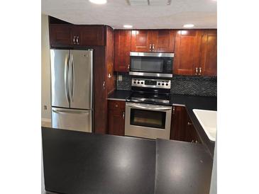 Well-equipped kitchen features stainless steel appliances and beautiful cherry wood cabinets at 7168 E Bank Dr # 7168, Tampa, FL 33617