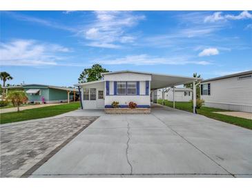 Charming single-story home with blue trim, carport, landscaped front, and paved driveway at 104 E Saint Johns Way, Apollo Beach, FL 33572