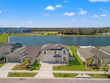 Stunning aerial view of a lakeside home with lush landscaping and a screened pool, creating a serene and private oasis at 11508 Sage Canyon Dr, Riverview, FL 33578