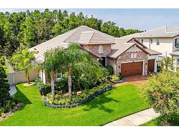 Beautiful home with a manicured lawn, lush landscaping, and a stone facade at 29118 Picana Ln, Wesley Chapel, FL 33543