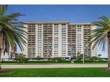 Stunning waterfront condo building featuring multiple balconies and lush landscaping with palm trees at 400 Island Way # 1402, Clearwater Beach, FL 33767