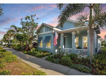 Charming coastal home featuring a manicured lawn, inviting porch, and beautiful landscaping at 610 Winterside Dr, Apollo Beach, FL 33572