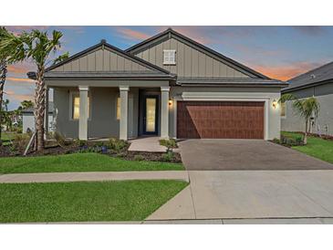 Charming single-story home featuring a two-car garage, well-manicured lawn, and inviting front porch at 10381 Tupper Cay Dr, San Antonio, FL 33576