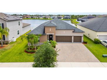 Beautiful single Gathering home featuring an attached three-car garage, lush landscaping, and a serene lake view at 11522 Sunburst Marble Rd, Riverview, FL 33579