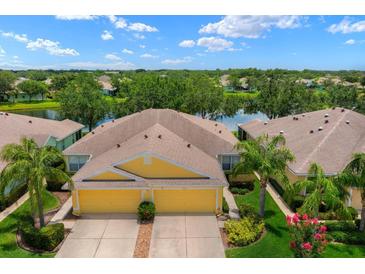 Stunning yellow home features a two-car garage, lovely landscaping, and a serene pond view, perfect for tranquil living at 11559 Captiva Kay Dr, Riverview, FL 33569