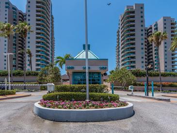 Community entrance with manicured flower bed, mature palm trees, and gated security at 1520 Gulf Blvd # 1505, Clearwater Beach, FL 33767