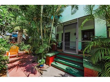 Inviting front porch with colorful accents and lush tropical plants and outdoor chairs at 214 Scotland St, Dunedin, FL 34698