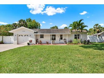 Charming white brick home featuring a lush green lawn, beautiful landscaping, and a welcoming front entrance at 5008 Stolls Ave, Tampa, FL 33615