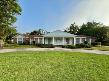 Charming brick home with a manicured lawn, covered porch with columns, and a circular driveway at 1002 W Pinedale Dr, Plant City, FL 33563