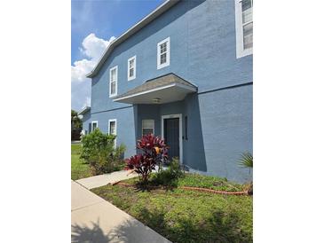 Two-story townhome with a blue exterior, covered entrance, and landscaped front yard at 13157 Kings Crossing Dr, Gibsonton, FL 33534