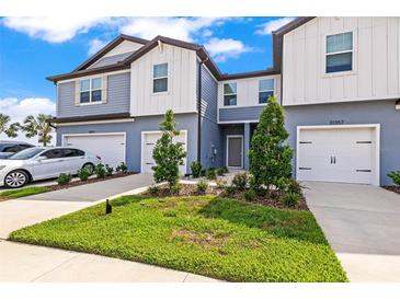Charming townhome with well-manicured lawn, two-car garage, and modern facade at 31355 Amberview Bnd, Wesley Chapel, FL 33545