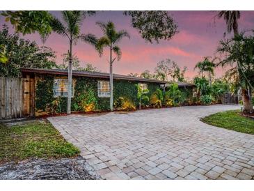 Charming single-story home with lush, green vine-covered facade and paver driveway surrounded by mature landscaping at 4301 S Lockwood Ridge Rd, Sarasota, FL 34231