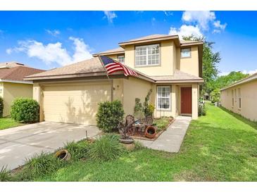 Inviting two-story home featuring a well-manicured lawn, attached garage and patriotic American flag at 5525 Turtle Crossing Loop, Tampa, FL 33625