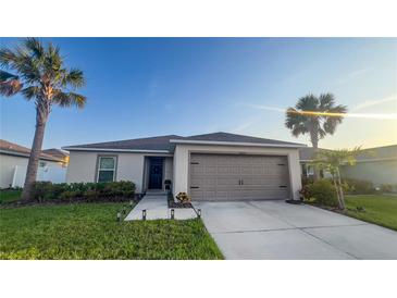 Charming single-story home featuring a manicured lawn and two-car garage at 10123 Carp Hollow Rd, Sun City Center, FL 33573