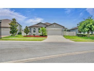 Charming single-story home with well-maintained landscaping, a paved driveway, and a two-car garage at 12653 Palapa Loop, Spring Hill, FL 34610