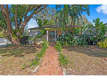 Charming single-story home with lush landscaping and a welcoming brick pathway at 1402 E Mohawk Ave, Tampa, FL 33604