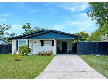 Charming single-story home with a well-manicured lawn, and a carport with chairs at 2606 E 97Th Ave, Tampa, FL 33612