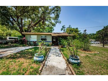 Charming home featuring a welcoming front yard with mature landscaping and a paved walkway at 6618 N 11Th St, Tampa, FL 33604