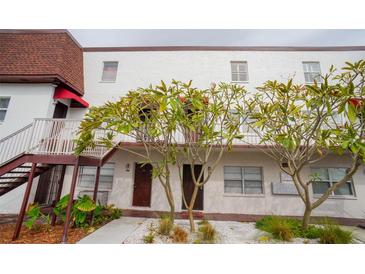 Condo building with white facade, dark trim, exterior stairs, and landscaping at 9217 Tudor Dr # A106, Tampa, FL 33615