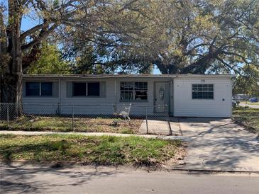Exterior view of a single-story home with a chain-link fence and mature trees in the front yard at 1716 Lancelot Loop, Tampa, FL 33619