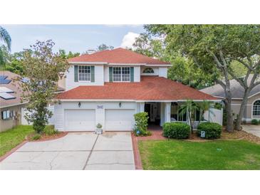 Charming two-story home boasts a red roof, a two-car garage, and a well-manicured lawn surrounded by mature trees at 2015 Long Branch Ln, Clearwater, FL 33760