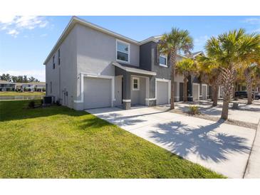 Modern townhome featuring an attached garage, a well-manicured lawn and swaying palm trees at 3334 Pleasant Willow Ct, Brandon, FL 33511