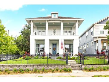 Charming two-story home with a welcoming porch, a well-manicured lawn, and decorative landscaping at 702 34Th N Ave, St Petersburg, FL 33704