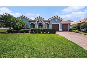 Charming blue home features a well-manicured lawn, lush landscaping, and a brick driveway leading to a two-car garage at 10645 Ruffino Ct, Trinity, FL 34655
