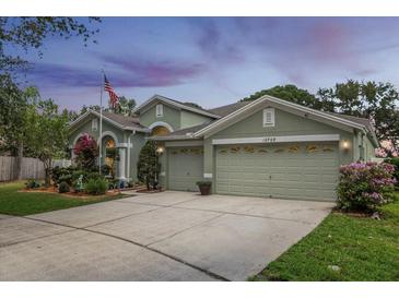 Charming single-Gathering home with a three-car garage, green lawn, and colorful landscaping at 10709 Rockledge View Dr, Riverview, FL 33579