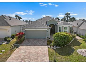 Beautiful single-story home featuring a brick driveway, attached garage, and tropical landscaping at 1110 Jasmine Creek Ct, Sun City Center, FL 33573