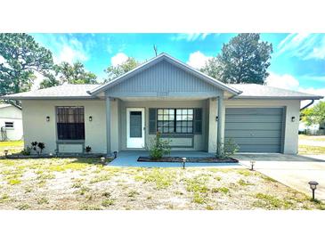 Charming single-story home featuring a well-maintained lawn, attached garage, and inviting front entrance at 13100 Serpentine Dr, Hudson, FL 34667