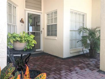 Inviting front porch with brick flooring, potted plants, and a charming entrance door at 14840 Shipwatch Trce # 1924, Largo, FL 33774