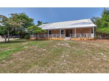 Charming single-story home with a metal roof, inviting front porch, and well-maintained lawn at 15625 Olney Ln, Spring Hill, FL 34610