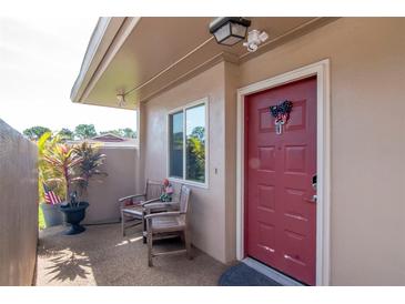 Inviting front porch with two chairs, plants, and a red front door, creating a warm welcome at 2444 Laurelwood Dr # A, Clearwater, FL 33763