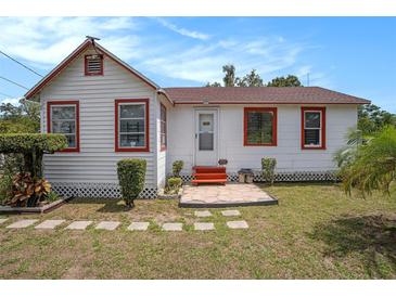 Charming home showcasing a white exterior with red trim and a well-maintained front lawn at 3405 E Diana St, Tampa, FL 33610