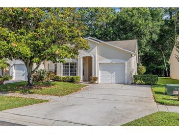 Charming single-story home with a well-manicured lawn, mature tree, and attached garage at 3512 Tealwood Cir, Palm Harbor, FL 34685