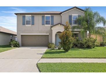 Two-story home featuring a two-car garage, manicured lawn, and tropical landscaping at 7170 Samuel Ivy Dr, Tampa, FL 33619