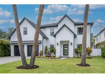 Stunning two-story modern home with a black trim, three-car garage, and beautiful landscaping at 4111 W Swann Ave, Tampa, FL 33609