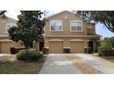 Inviting townhome with tan stucco, attached garages, and well-maintained landscaping in a quiet neighborhood at 11839 Castine St, New Port Richey, FL 34654