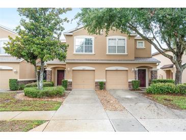 Two-story tan home featuring a well-manicured lawn, two-car garage, and charming stone accents at 11839 Castine St, New Port Richey, FL 34654