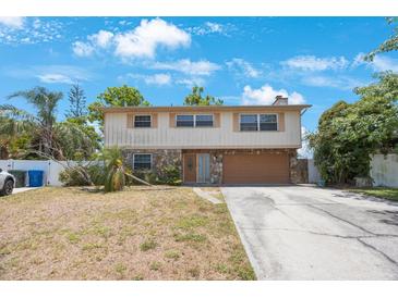 Two-story home with stone accents, a two-car garage, and a spacious front yard under a bright blue sky at 12803 126Th Ter, Largo, FL 33774
