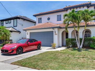 Charming two-story home with a clay tile roof, manicured lawn, and a red luxury sports car at 3003 W Leila Ave, Tampa, FL 33611