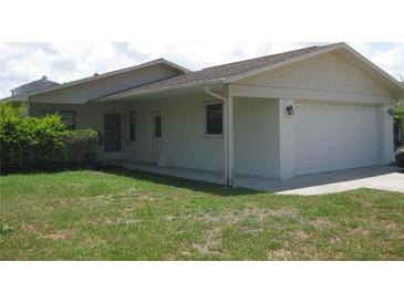 A single-story home with a white exterior, green lawn, and an attached two-car garage at 4673 Dewey Dr, New Port Richey, FL 34652