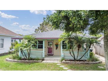 Charming home with light yellow siding, covered porch, and tropical landscaping with palm trees at 507 4Th Sw Ave, Largo, FL 33770