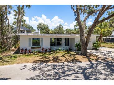 Charming single-story home with a well-manicured front yard, blue shutters and lush landscaping at 5270 Miller Bayou Dr, Port Richey, FL 34668