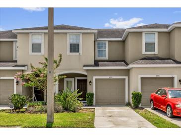Close up of tan townhomes with garages and a red car parked in front at 6924 Towne Lake Rd, Riverview, FL 33578