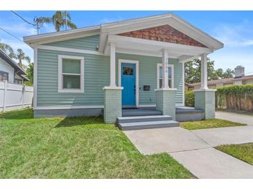 Charming single-story home featuring a quaint front porch, a blue front door, and well-maintained landscaping at 1006 E 23Rd Ave, Tampa, FL 33605
