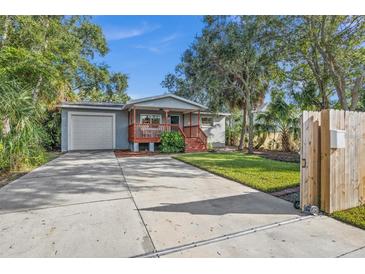 Charming home with a covered front porch, lush landscaping, and a spacious driveway leading to a one-car garage at 1045 28Th S Ave, St Petersburg, FL 33705