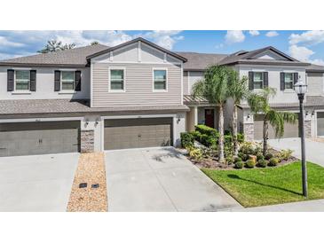 Charming two-story townhome featuring attached garages and beautifully landscaped front yard at 1396 White Fox Run, Lutz, FL 33549