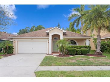 Charming single-story home boasts a well-manicured lawn, a two-car garage, and lush tropical landscaping at 14612 Corkwood Dr, Tampa, FL 33626